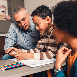 two parents helping their son with schoolwork