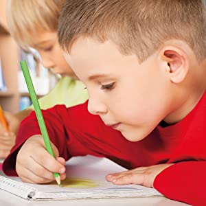 Boy in red jumper with green pencil practising his drawing skills